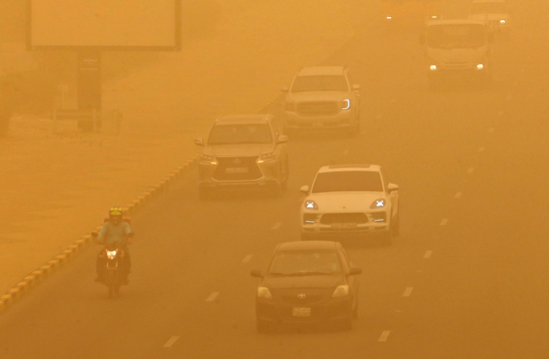 Cars drive amid a heavy sandstorm in Kuwait City on May 16, 2022. 