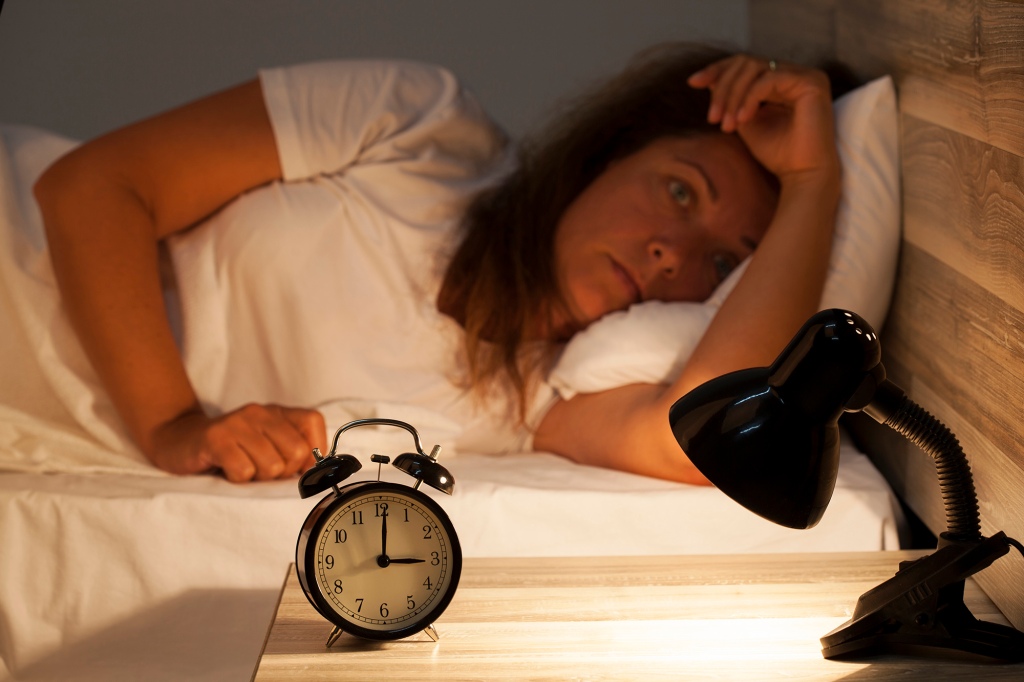 Woman lying in bed suffering from headache and  insomnia